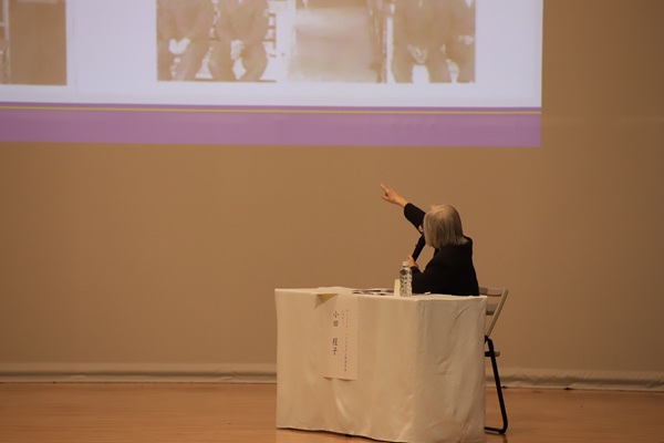 映像に映る写真から自身を指さすシスター